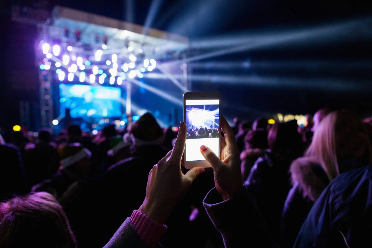 A girl is taking pictures of a street concert on the phone