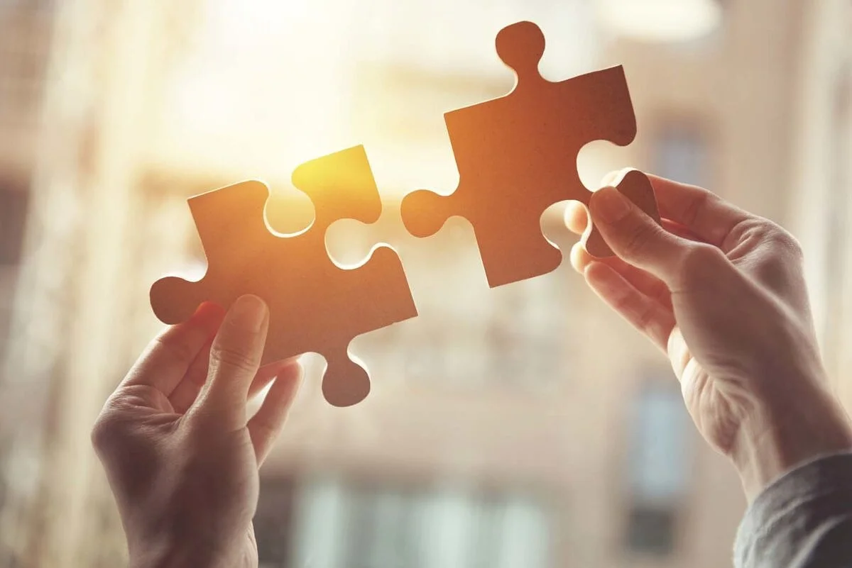 Businesswoman hand connecting jigsaw puzzle with sunlight effect