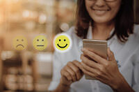 Businesswoman pressing face emoticon on virtual touch screen at smartphone .Customer service evaluation concept.